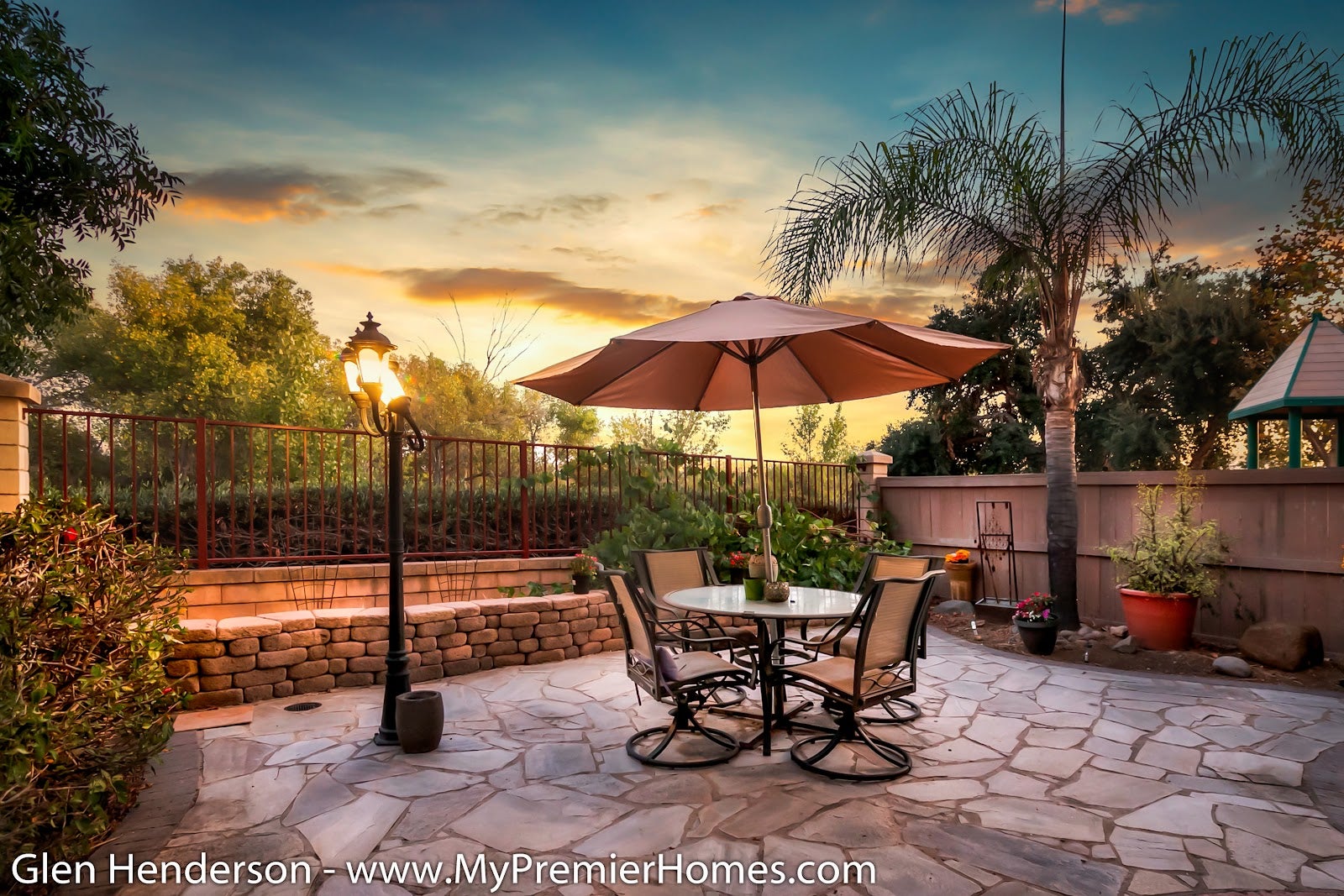 A backyard in Santee with a table and chairs under an umbrella at sunset.