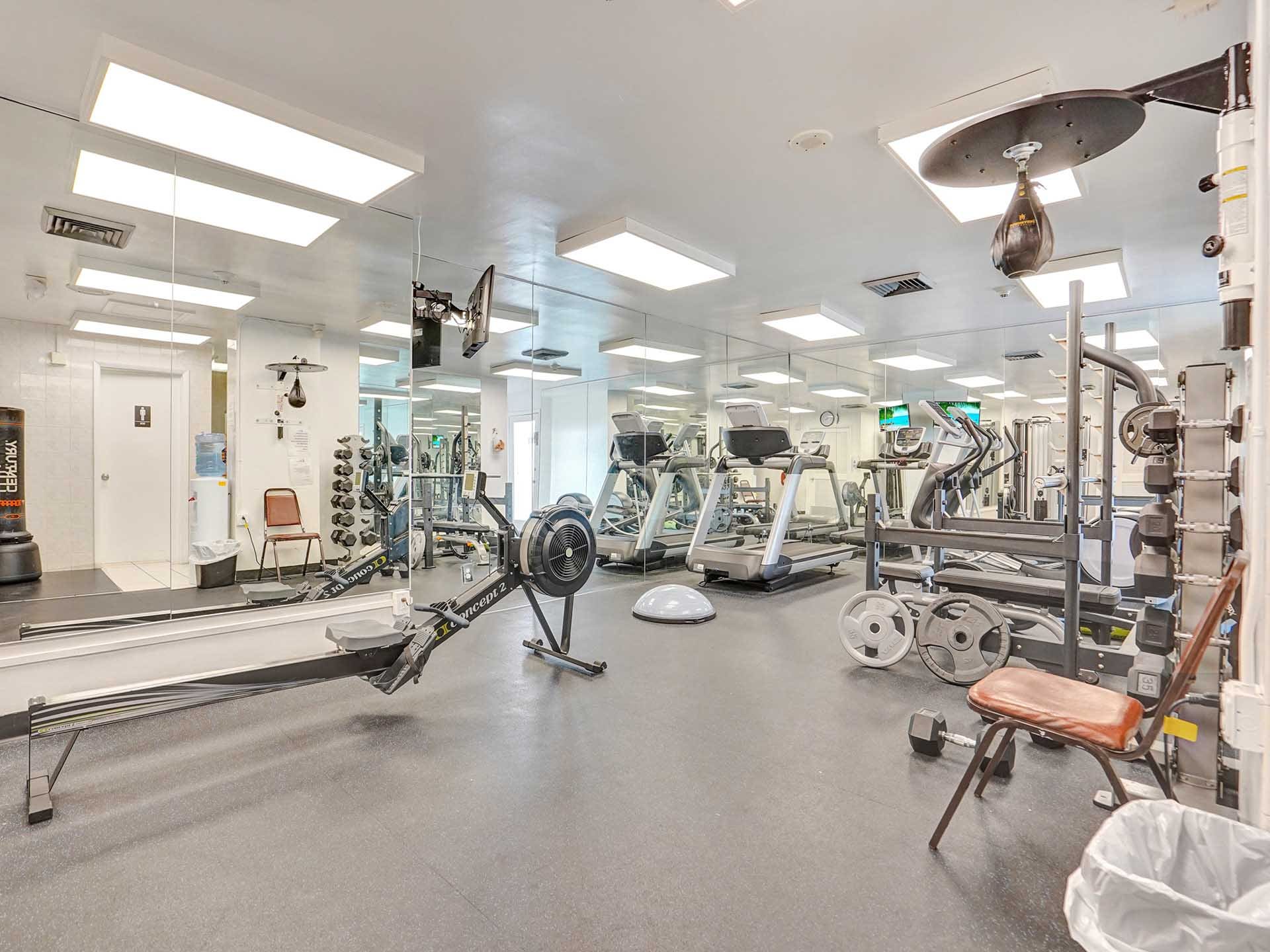 The fully equipped resident fitness center at Point of Americas, 2100 & 2200 S Ocean Lane, featuring free weights and cardio machines.