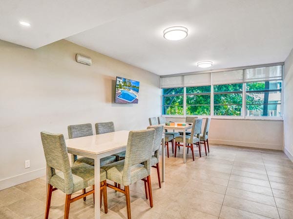 The bright and inviting community game room at East Point Towers, offering comfortable seating and scenic views overlooking the pool deck.