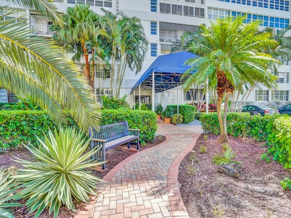 Beautifully landscaped tropical gardens and brick walkway leading to the secure, canopied entrance of East Point Towers in Fort Lauderdale.