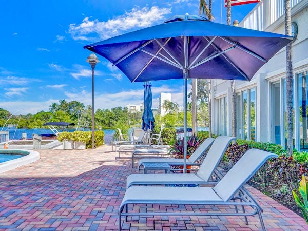 Relaxing poolside lounge chairs and shaded seating on the brick paver sun deck at East Point Towers, with scenic views of the water.