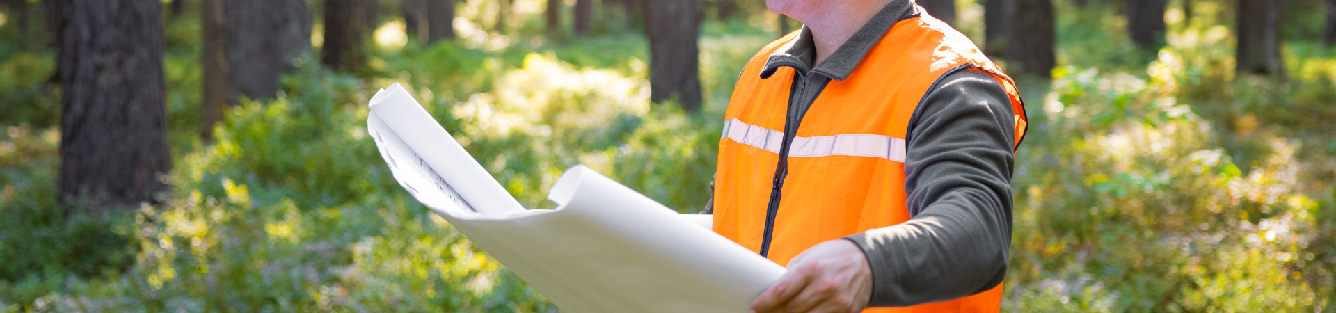 Engineer in the woods reviewing plan sheets