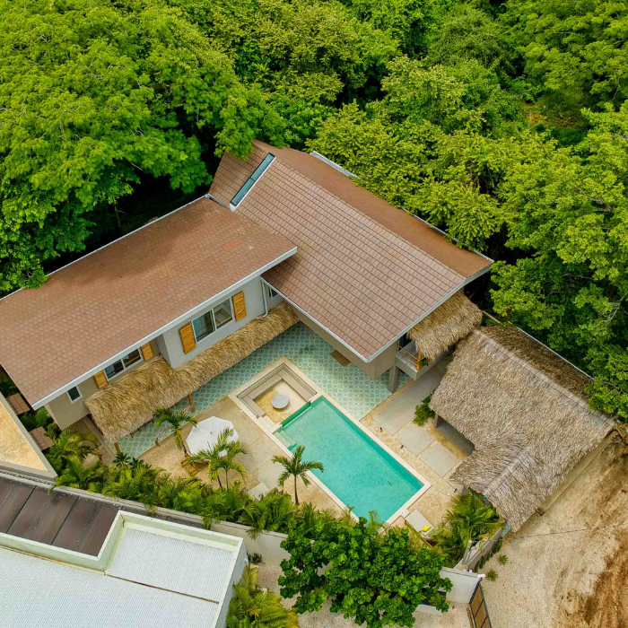 Drone view highlighting the central swimming pool, thatched roof details, and modern architecture of a Tamarindo luxury home.