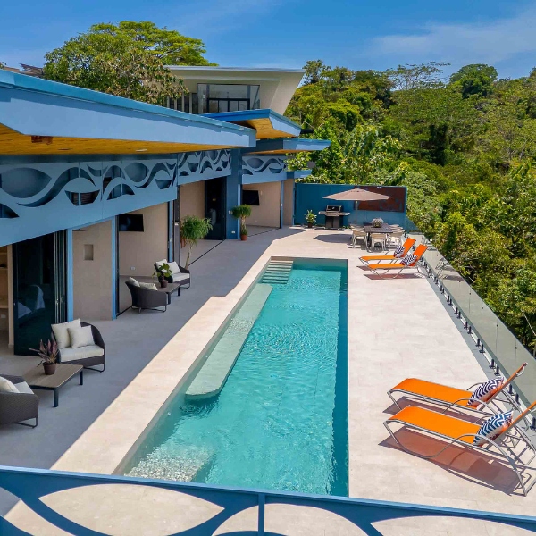alt: a house with a long pool with beach chairs alongside and jungle to the views