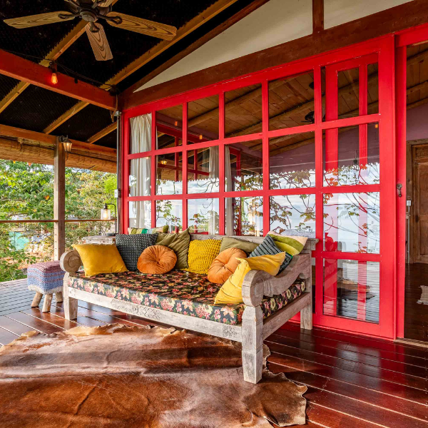 Ocean view terrace with daybed, colorful pillows, and red framed glass doors