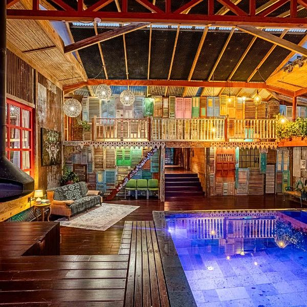 Luxury tropical home interior with indoor pool and reclaimed wood shutter wall