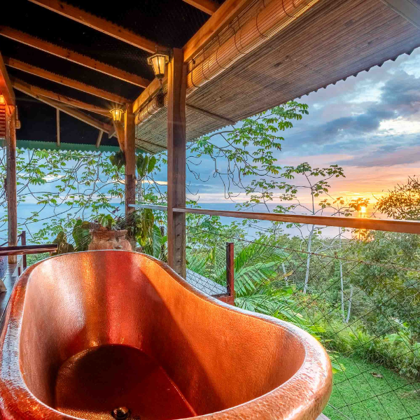 Copper soaking tub on covered balcony with ocean and jungle views