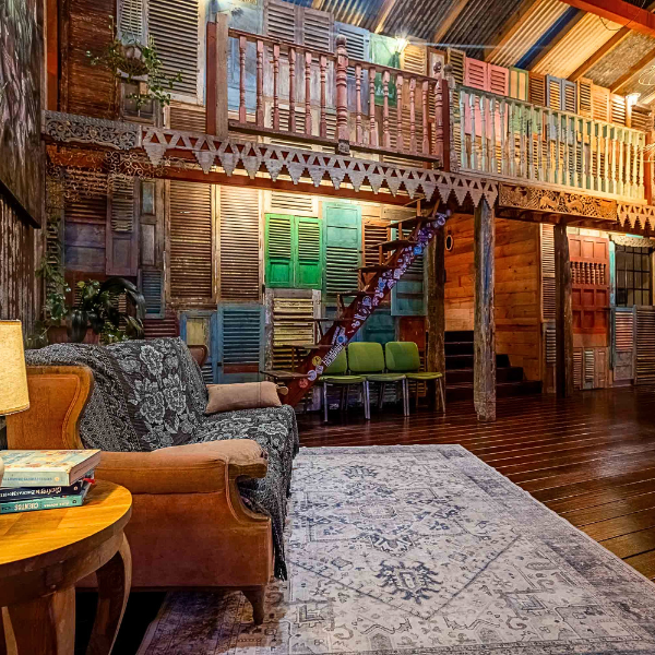 Rustic living area with reclaimed shutter wall, staircase, and wood floors