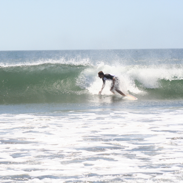 Surfer riding a wave on a sunny beach in Costa Rica's Pacific coast