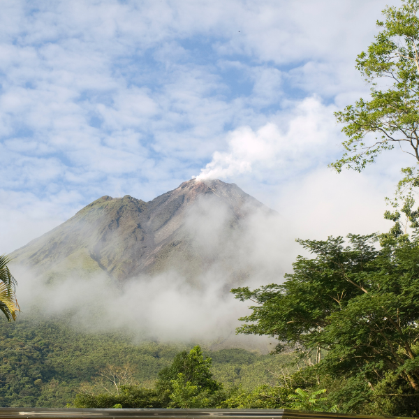 Arenal Volcano rising above the rainforest with clouds and lush green trees in Costa Rica