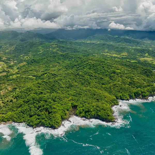 Aerial view of Costa Rica's jungle coastline with turquoise ocean waves and mountain backdrop
