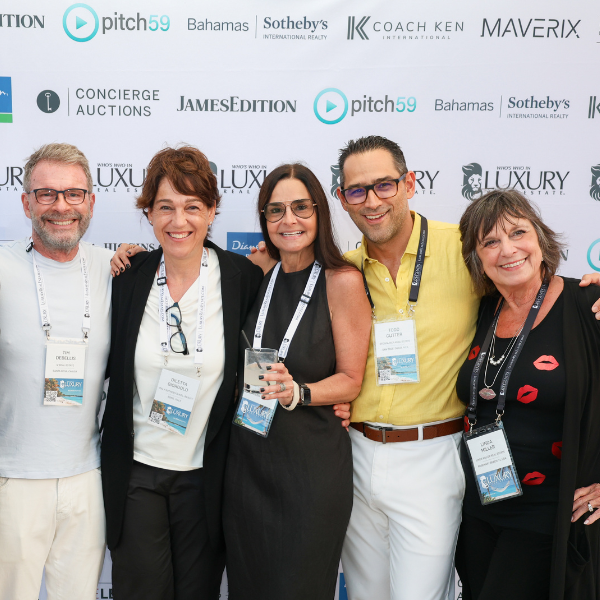 Five real estate professionals posing together in front of a branded media wall featuring logos including Who's Who in Luxury Real Estate, pitch59, Bahamas Sotheby's International Realty, and Maverix