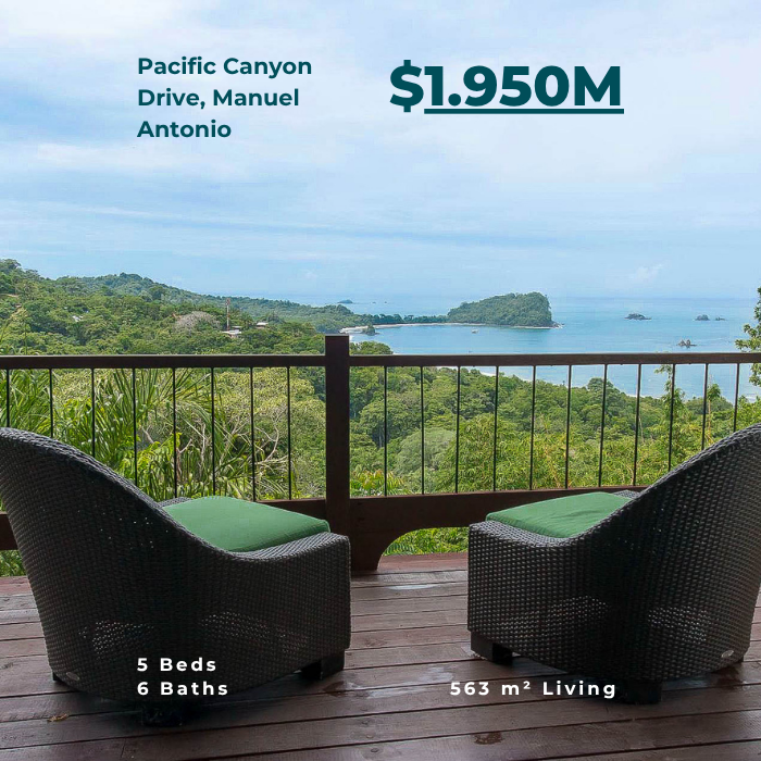 Ocean view balcony with two chairs overlooking lush hills and coastline in the distance.