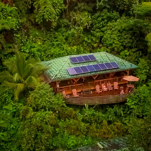 Luxury eco lodge surrounded by Costa Rica rainforest featuring solar panels, wooden architecture, and elevated jungle views.