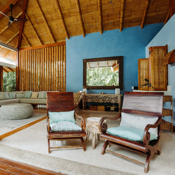 Spacious lounge with bamboo accents, blue feature wall, rustic chairs, and tropical-inspired interior blending elegance with natural Costa Rican style.