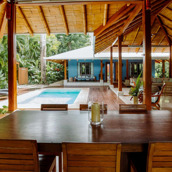 Kitchen entrance with wooden sliding doors, open shelving, stainless steel appliances, and natural textures enhancing a tropical modern design