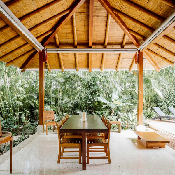Cozy bedroom with vaulted bamboo ceiling, two beds, woven rug, and artwork, blending comfort and tropical Santa Teresa charm.
