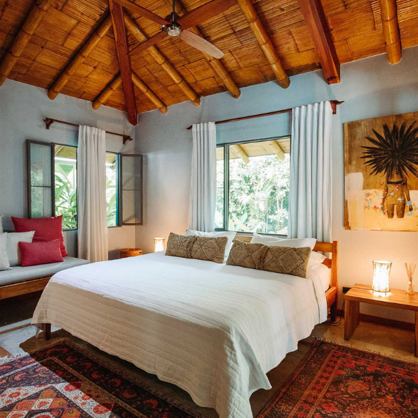 Luxury bedroom with bamboo ceiling, king bed, soft lighting, tropical garden views, and rustic-chic decor for a serene retreat.