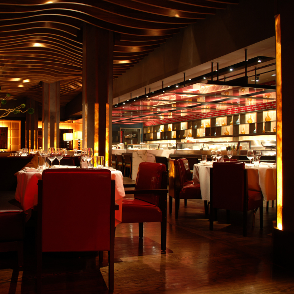 An elegant fine-dining restaurant interior with warm lighting, red velvet chairs, and a luxurious modern atmosphere.