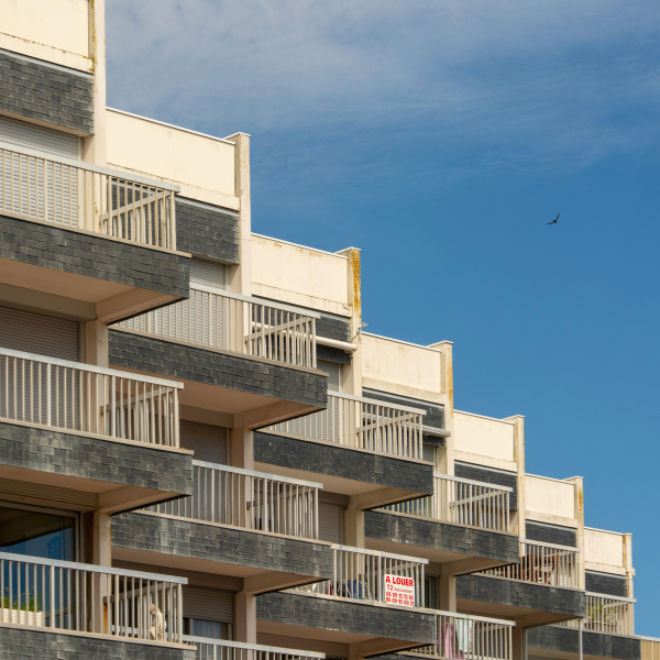 Modern mixed-use building with stepped balconies against a blue sky.