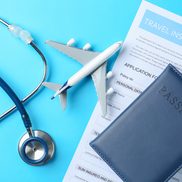 Travel insurance and medical travel concept with passport, airplane model, stethoscope, and travel application documents on a blue surface.