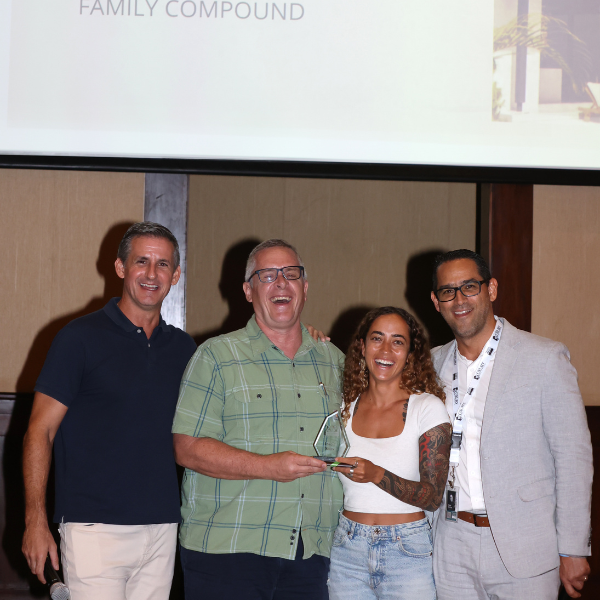 Group of four people smiling while presenting an award on stage during a real estate or corporate recognition event.