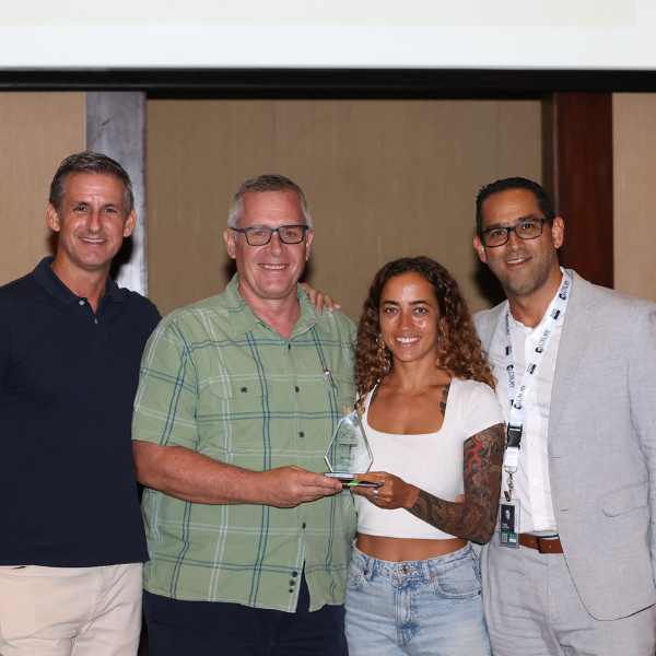 Award presentation photo featuring four people posing together while holding a glass trophy at a professional event or ceremony.