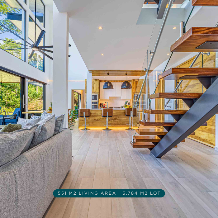 Open concept living room with floating staircase, double height ceilings, and modern kitchen.