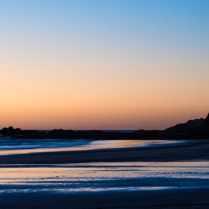 Peaceful beach at sunset with reflective shoreline, calm ocean water, and pastel evening sky in Costa Rica.