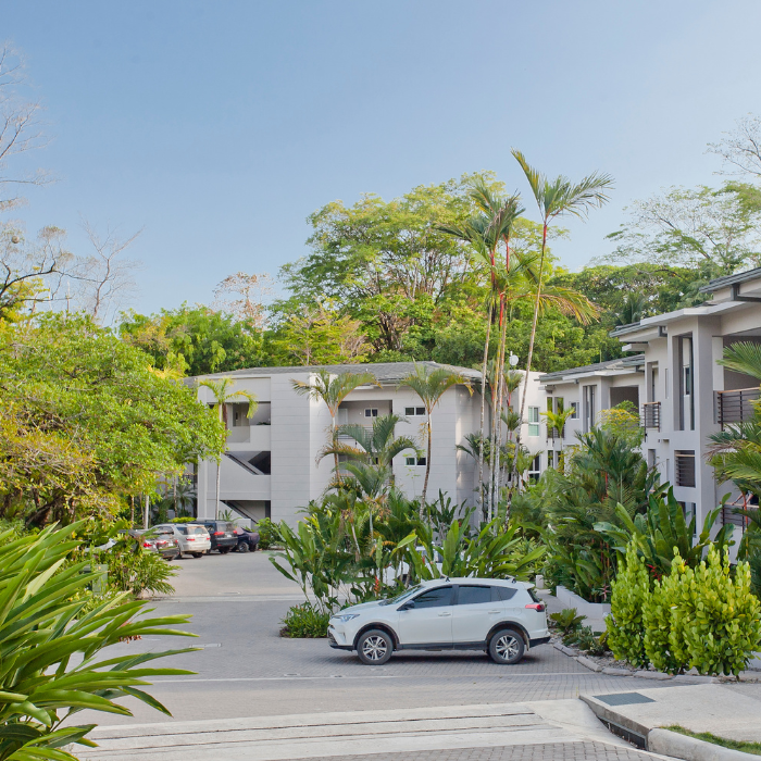 Contemporary luxury condominium building with spacious terraces overlooking greenery and surrounding urban residences.